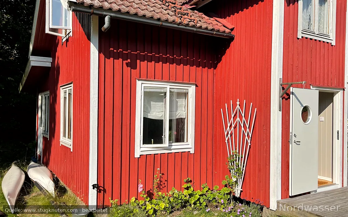 Rött stenhuggartorp nära hav och skog