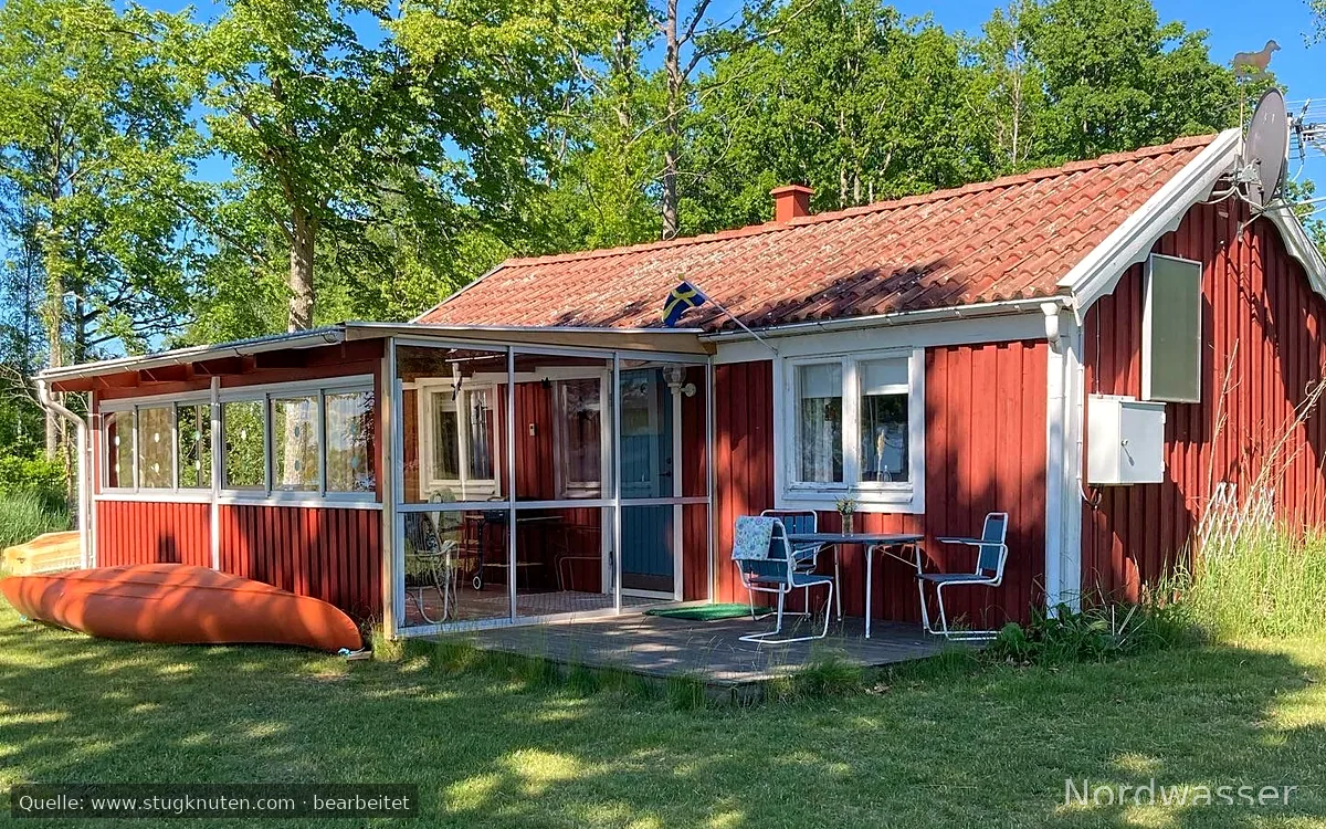 Röd liten stuga vid sjön